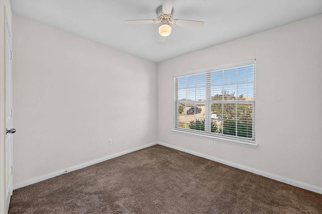 14276 Greenhaw Lane, Dallas, TX 75253 Neutral-toned interior featuring wall-to-wall carpeting, a multi-pane window with installed blinds, and a central ceiling fan with an integrated light fixture