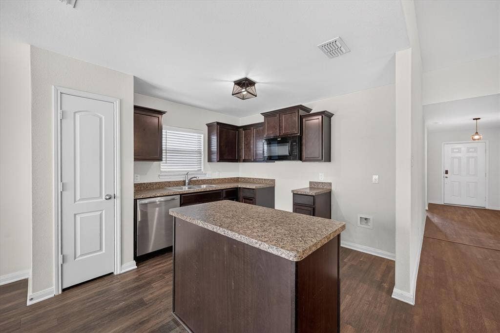 14276 Greenhaw Lane, Dallas, TX 75253 Kitchen featuring dark wood-finish cabinetry, a center island, stone-finish countertops, stainless steel appliances, and wood-finish flooring