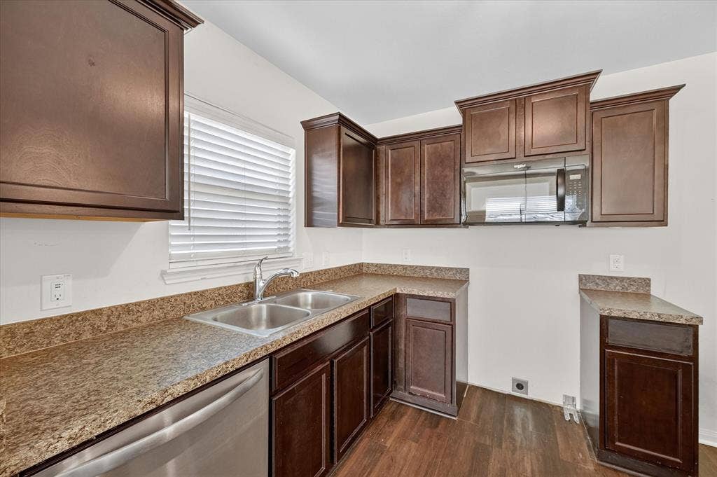 14276 Greenhaw Lane, Dallas, TX 75253 Kitchen featuring dark-finish cabinetry, stone-texture laminate countertops, stainless steel dual-basin sink, integrated over-the-range microwave, and wood-finish flooring