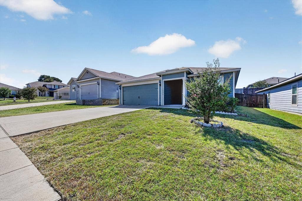 14276 Greenhaw Lane, Dallas, TX 75253 Single-story exterior featuring blue siding, a covered entryway, an attached two-car garage, and a concrete driveway