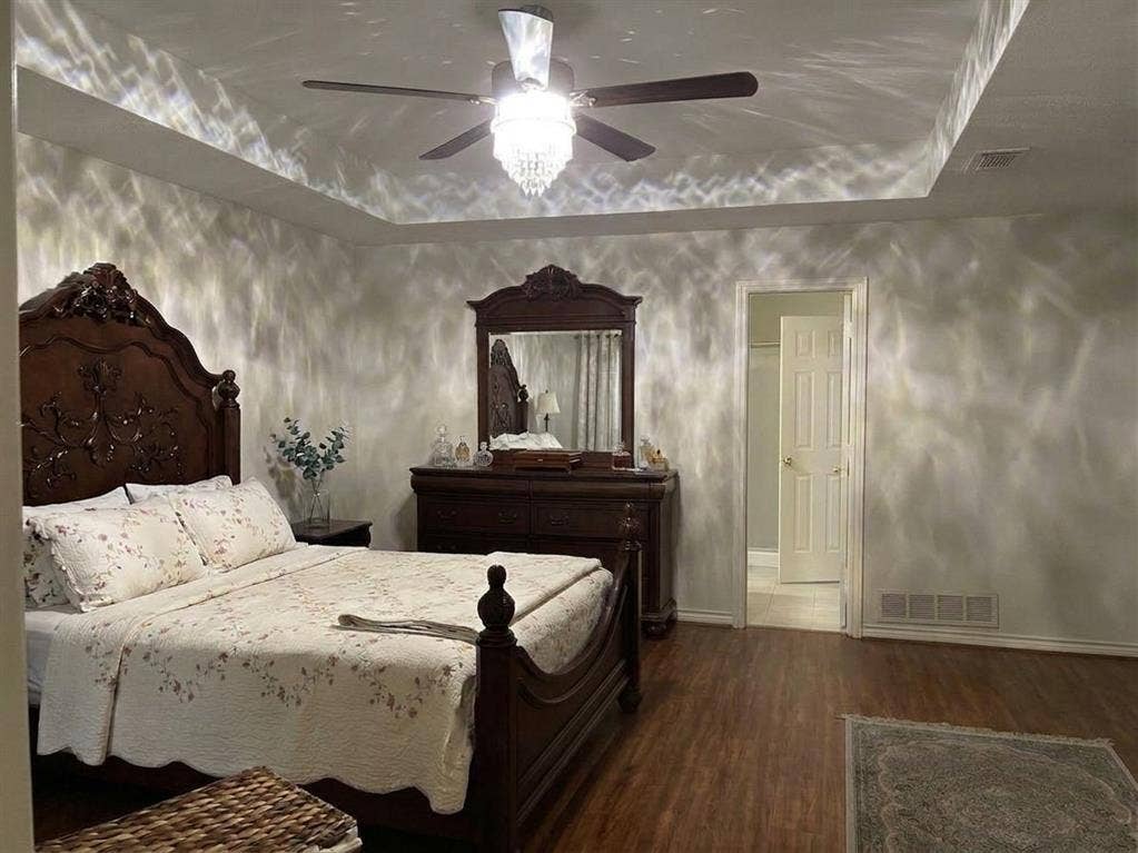 6011 Highplace Circle, Dallas, TX 75254 Tray ceiling featuring a central crystal-accented chandelier with integrated ceiling fan and wood-finish flooring