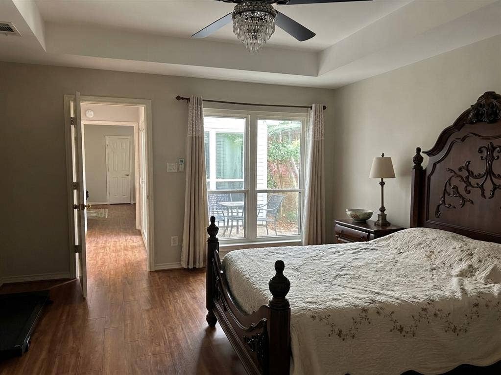 6011 Highplace Circle, Dallas, TX 75254 Tray ceiling featuring a central crystal-accented ceiling fan, wood-finish flooring, and large windows with exterior patio exposure