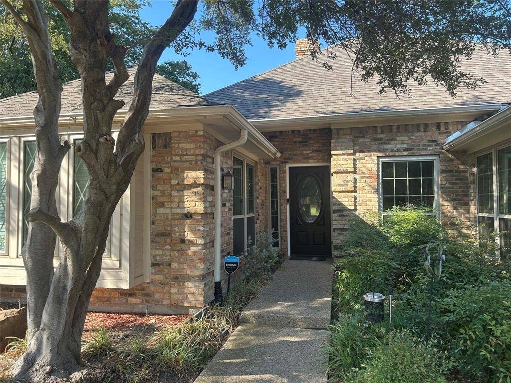 6011 Highplace Circle, Dallas, TX 75254 Brick exterior facade featuring a multi-gabled roofline, oval-insert front door, and concrete entryway path