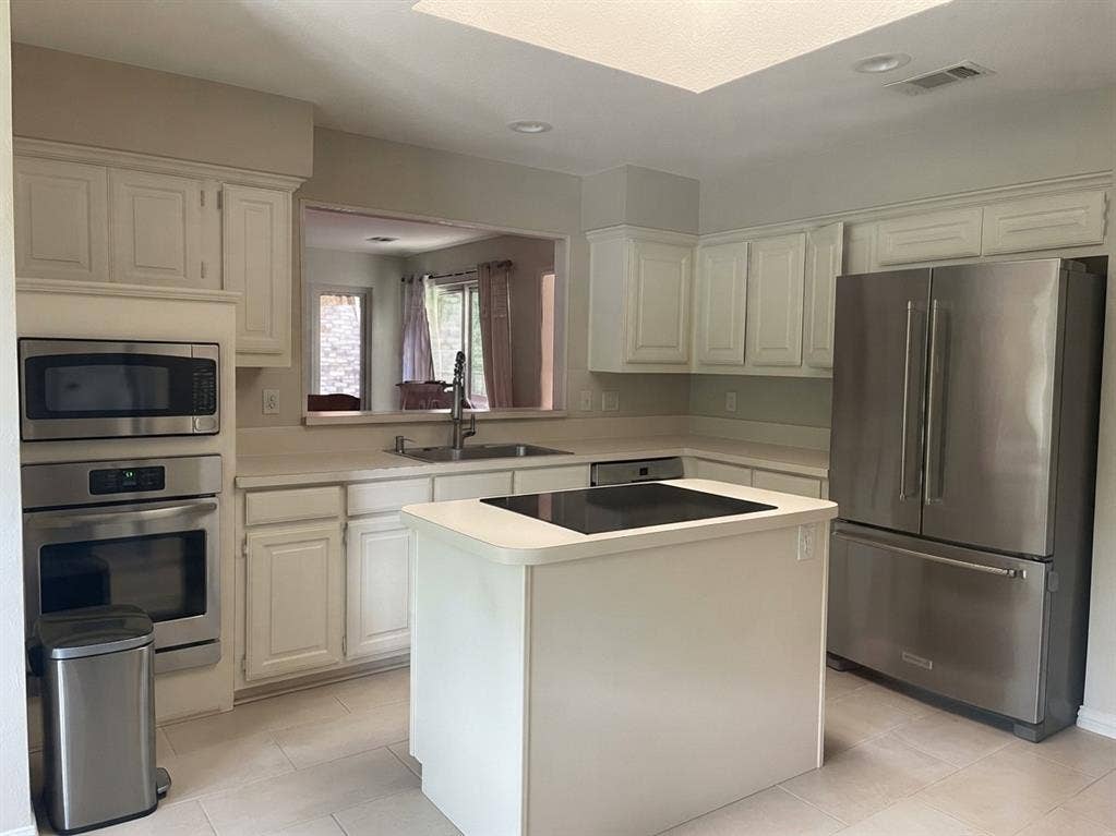 6011 Highplace Circle, Dallas, TX 75254 Kitchen featuring a central island with a glass cooktop, stainless steel appliances, recessed ceiling lighting, light-toned cabinetry, and tile flooring