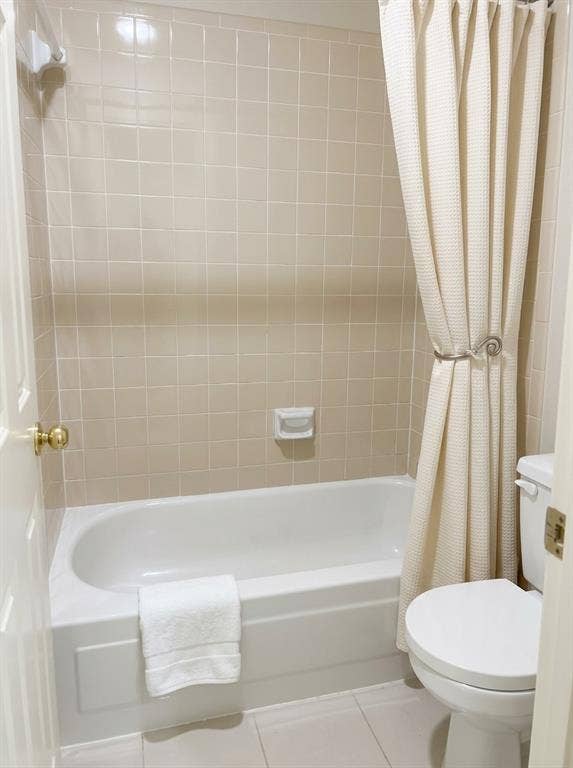 6011 Highplace Circle, Dallas, TX 75254 Bathtub with a white acrylic surround, integrated soap dish, ceramic wall tile, and porcelain toilet