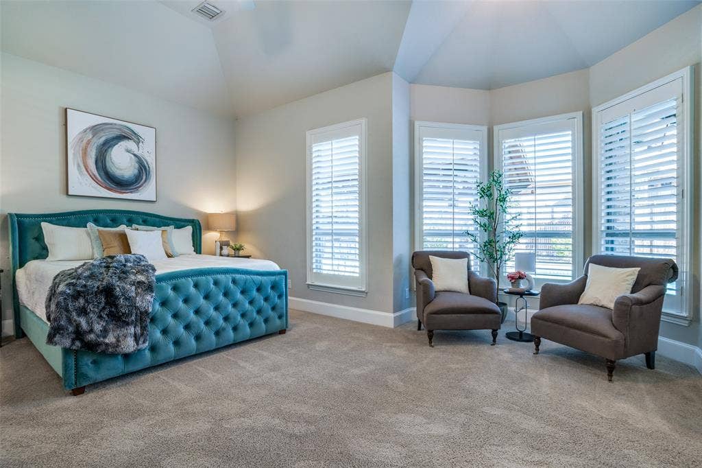 Big primary bedroom featuring lofted ceiling and bay window sitting area