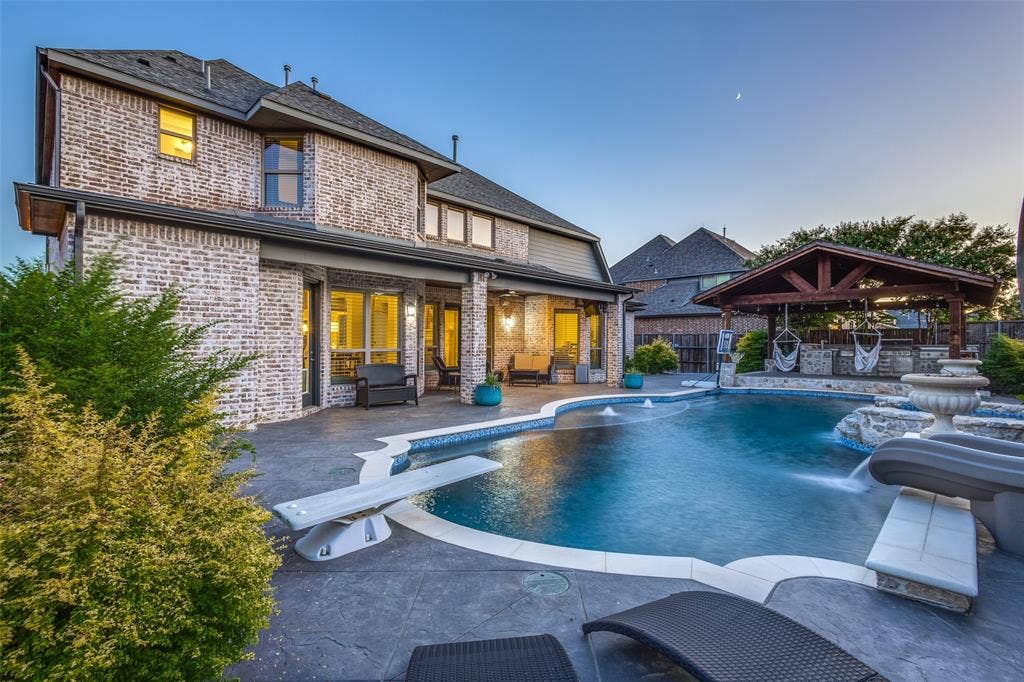 Pool at dusk featuring a diving board, a gazebo, a patio area, and outdoor lounge area