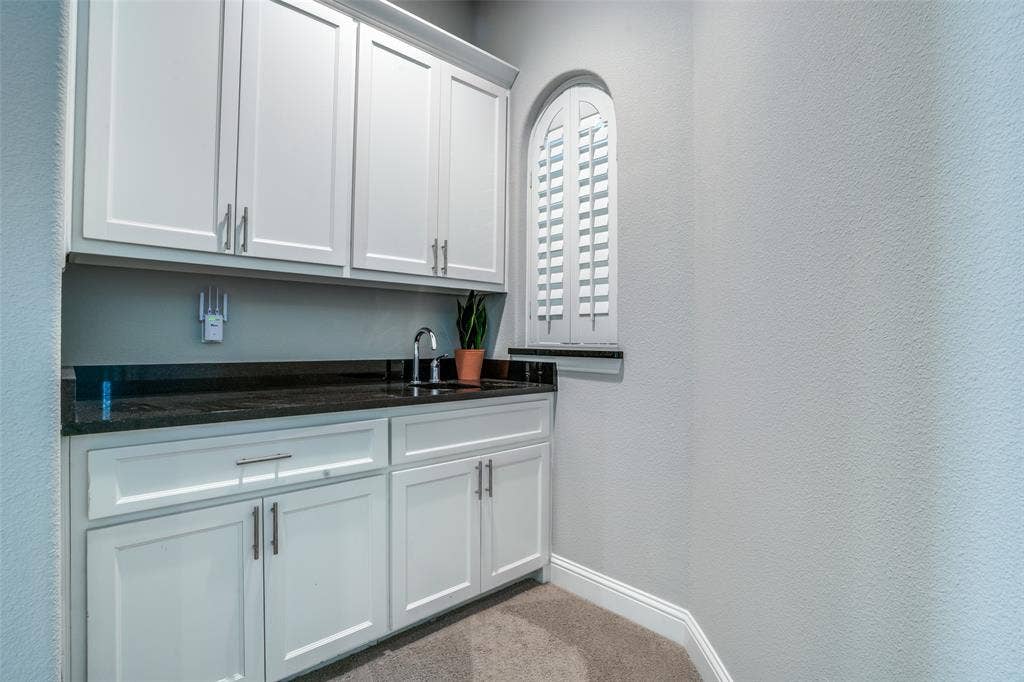 Upstairs wet bar in the game room featuring a sink and a pass thru window in the media room