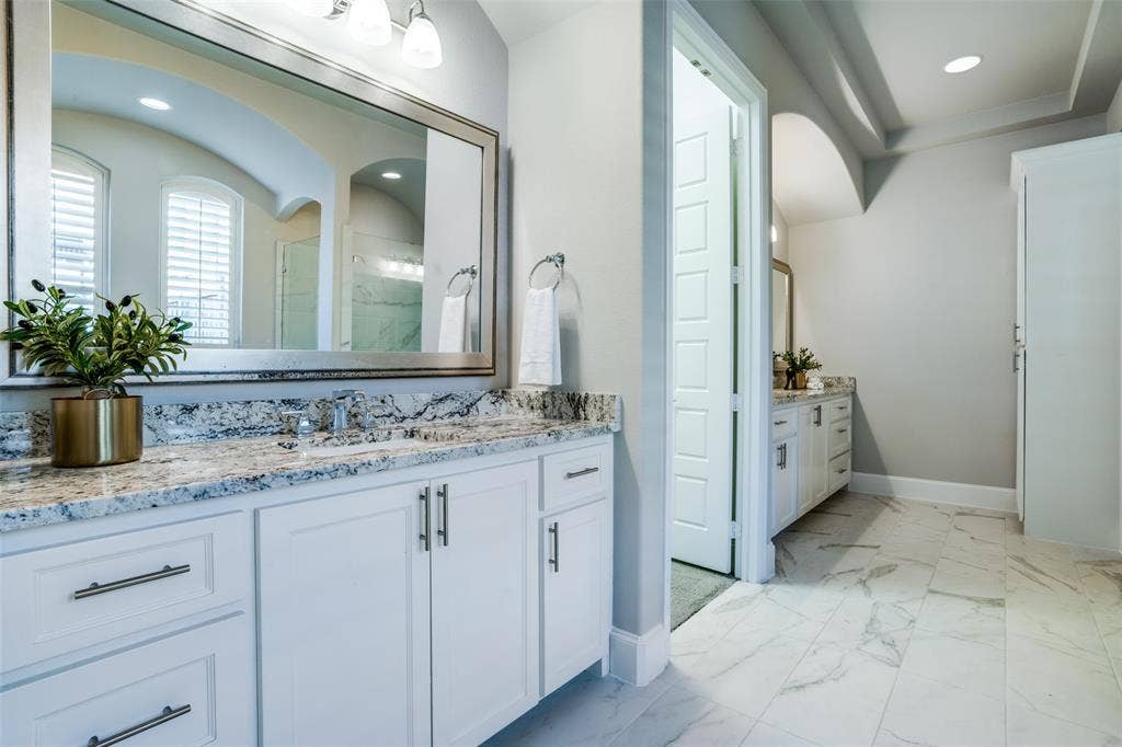 Bathroom featuring split vanities with lots of cabinets and framed mirrors