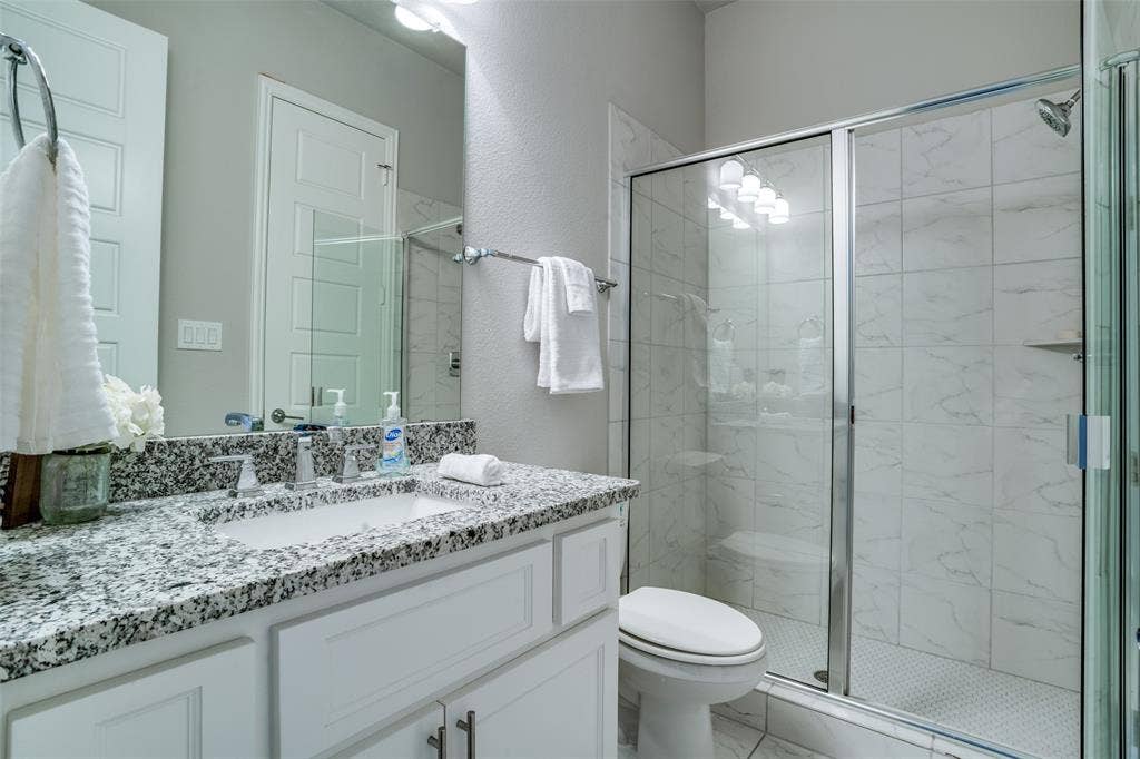 Downstairs bathroom featuring oversized vanity with granite countertops, walk in shower with enclosure.