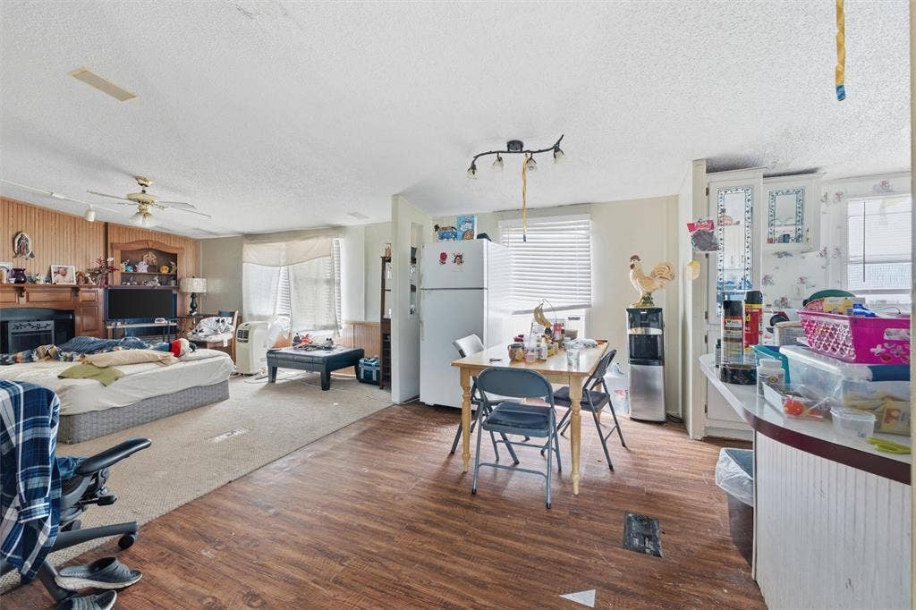 902 Old Church Rd, Waxahachie, TX 75165 Open-concept floor plan featuring wood-finish flooring, built-in fireplace mantle, ceiling fan, and white cabinetry with glass-panel inserts