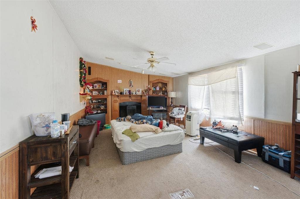 902 Old Church Rd, Waxahachie, TX 75165 Living area featuring wood-paneled walls, built-in shelving, a central fireplace mantle, and a ceiling fan