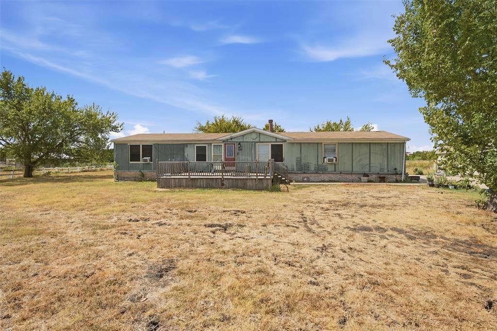 902 Old Church Rd, Waxahachie, TX 75165 Single-story residence featuring wood-paneled siding, an elevated wood deck, and expansive acreage with mature trees