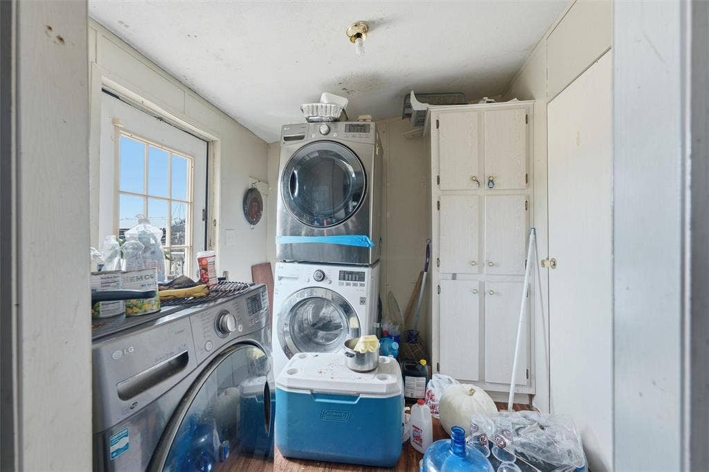 902 Old Church Rd, Waxahachie, TX 75165 Utility area featuring built-in floor-to-ceiling cabinetry, a multi-pane exterior door, and stacked laundry appliances