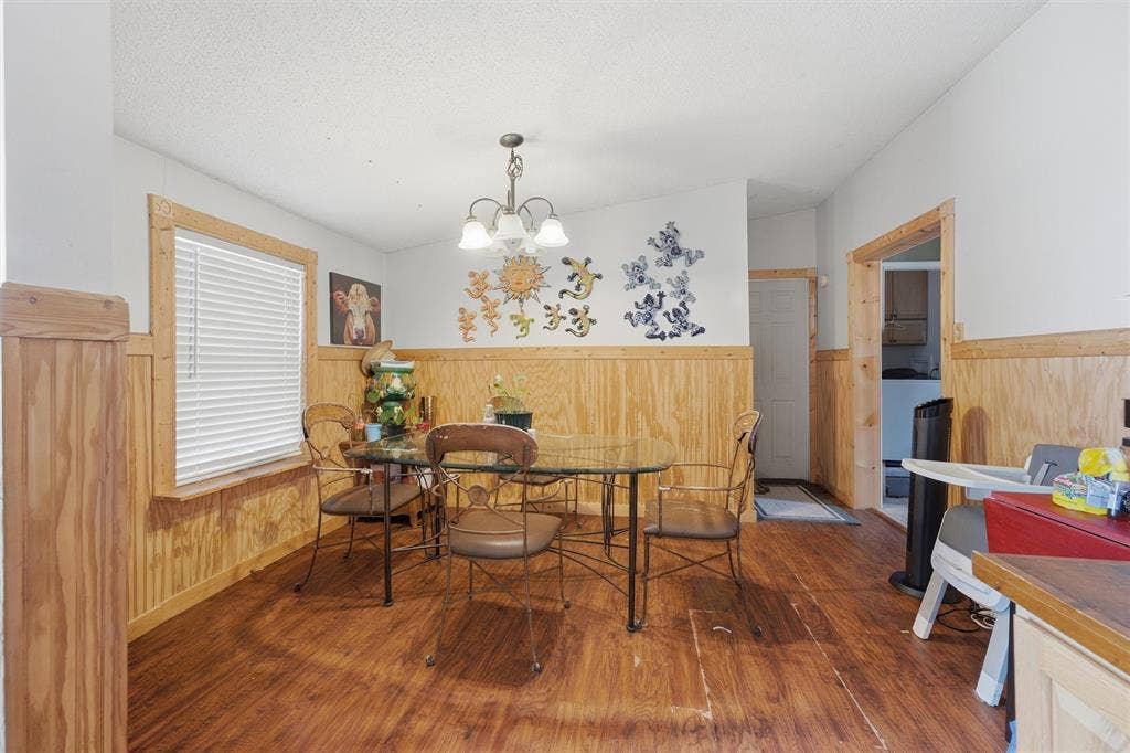 902 Old Church Rd, Waxahachie, TX 75165 Dining area featuring wood-finish flooring, wainscoting, an overhead chandelier, and a multi-pane window