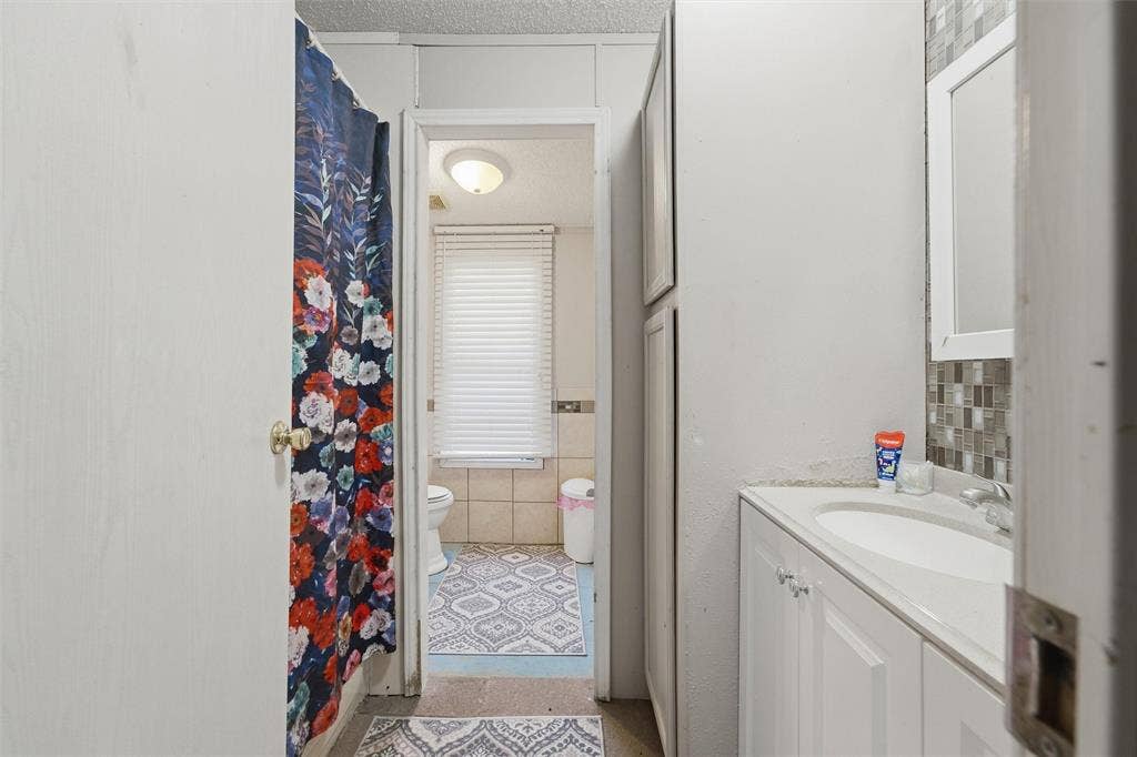 902 Old Church Rd, Waxahachie, TX 75165 Bathroom featuring a white vanity cabinet with an integrated sink and tiled backsplash, complemented by full-height built-in storage cabinetry