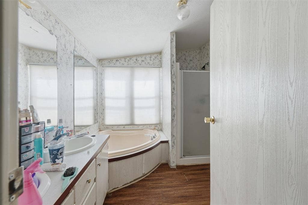 902 Old Church Rd, Waxahachie, TX 75165 Bathroom featuring a corner soaking tub with a surrounding deck, a wood-finish floor, a wall-to-wall vanity mirror, and a standalone shower stall