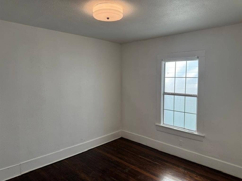 422 S Glasgow Drive, Dallas, TX 75223 White walls with dark wood-finish flooring, featuring a single-pane window with white trim and a flush-mount ceiling light