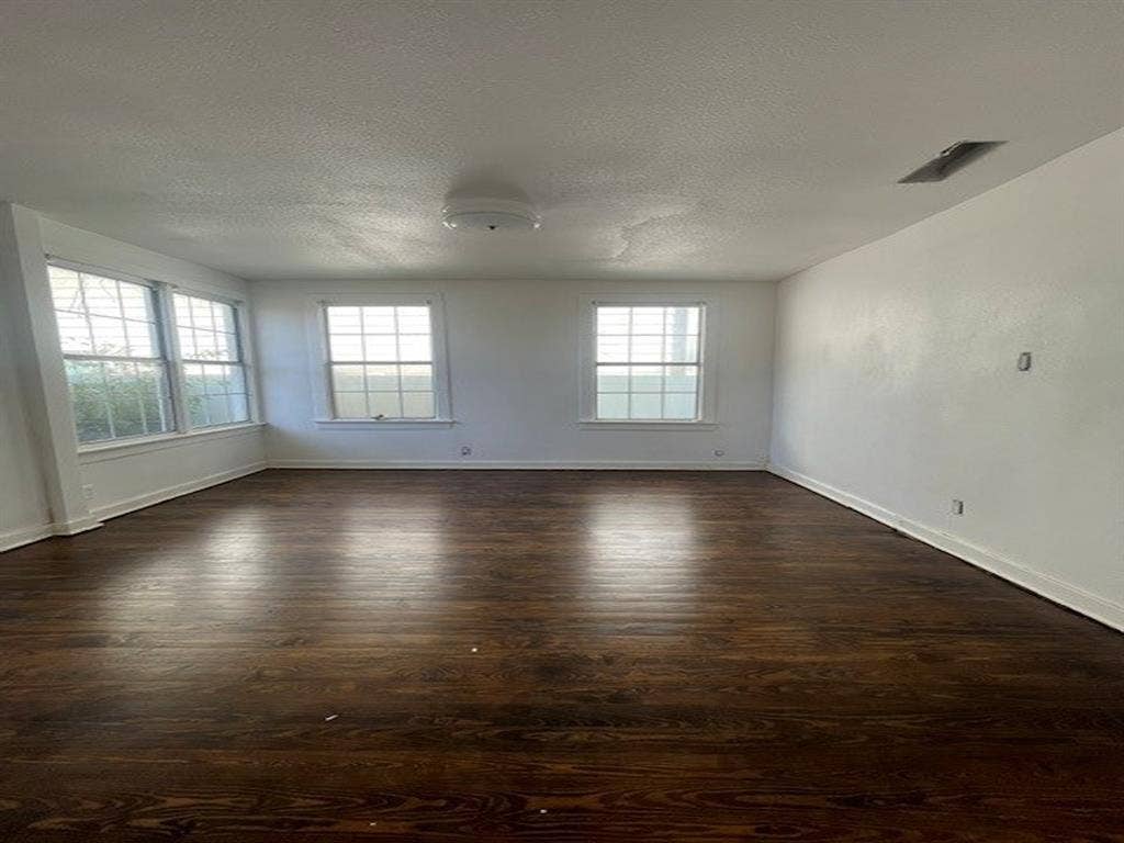 422 S Glasgow Drive, Dallas, TX 75223 Expansive room with dark wood-finish flooring, multiple windows, white painted walls, and a flush-mount ceiling light fixture