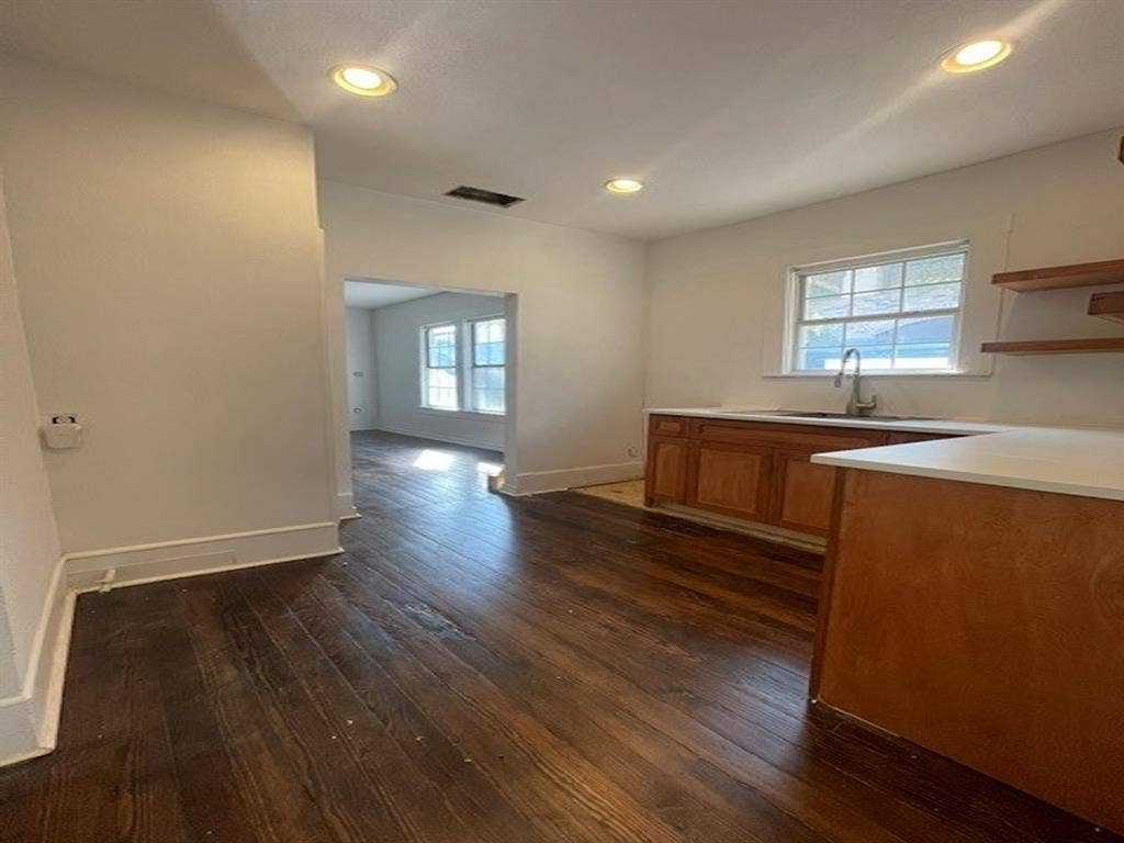 422 S Glasgow Drive, Dallas, TX 75223 Wood-finish flooring throughout, recessed ceiling lighting, light-toned cabinetry, white countertops, and a stainless steel sink with a pull-down faucet
