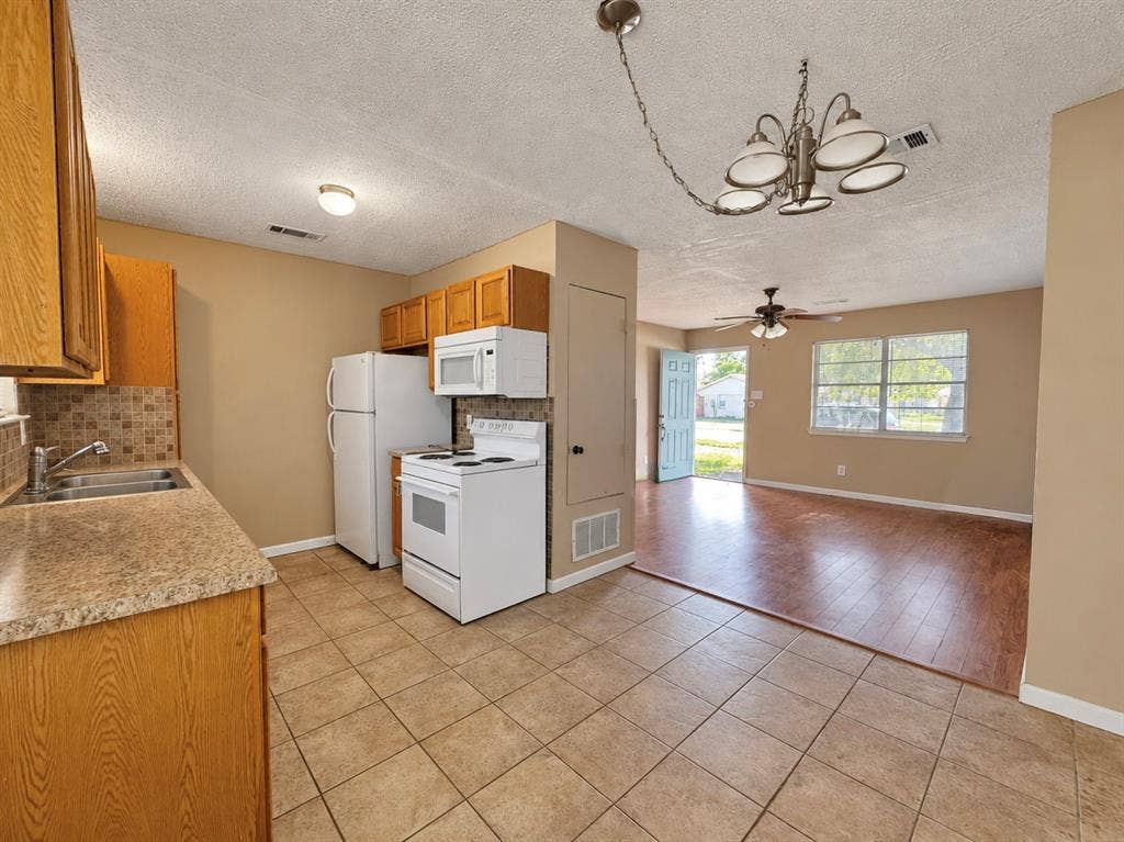 2418 Fulton Drive, Mesquite, TX 75150 Kitchen featuring cabinetry with light wood finish, tile flooring, stone-finish countertops, mosaic tile backsplash, and a multi-arm hanging chandelier