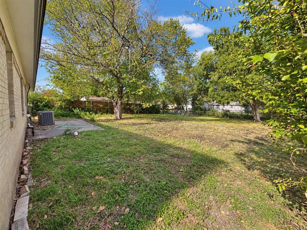 2418 Fulton Drive, Mesquite, TX 75150 Backyard featuring a concrete patio, light-toned brick exterior, mature trees, and perimeter fencing