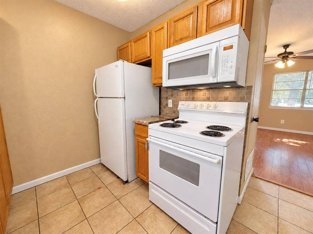 2418 Fulton Drive, Mesquite, TX 75150 Kitchen featuring natural wood cabinetry, white appliances, a tiled backsplash, and ceramic tile flooring