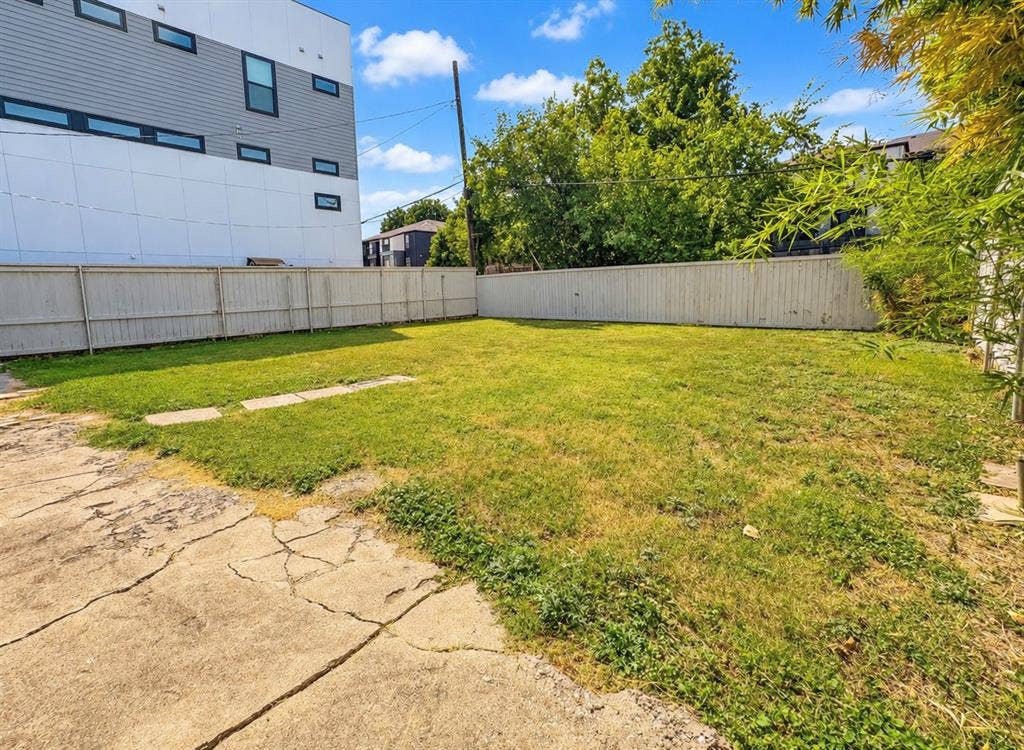 4227 Delano Place, Dallas, TX 75204 Fenced backyard featuring a grass lawn, concrete hardscaping, and mature trees
