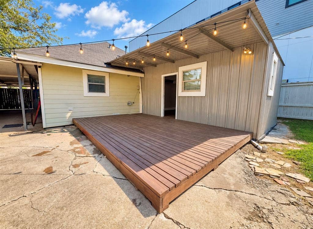 4227 Delano Place, Dallas, TX 75204 Wood-finish platform deck with an attached corrugated metal awning, overhead string lighting, and exterior lap siding