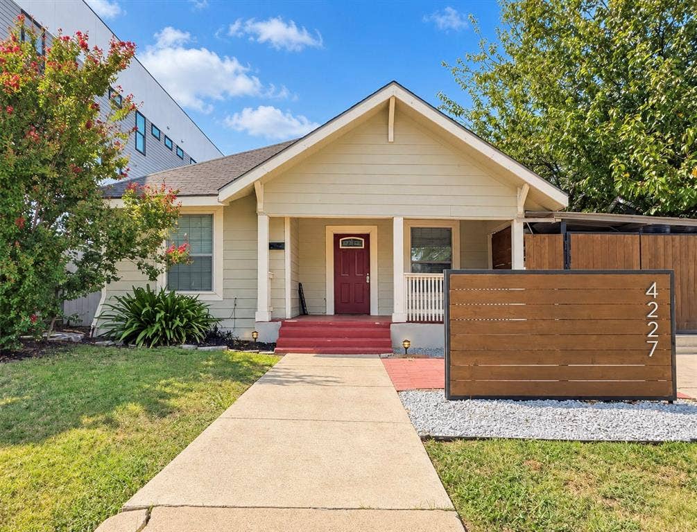 4227 Delano Place, Dallas, TX 75204 Single-story exterior featuring horizontal siding, a covered front porch with squared columns, a solid wood-finish slat privacy screen, and a concrete walkway