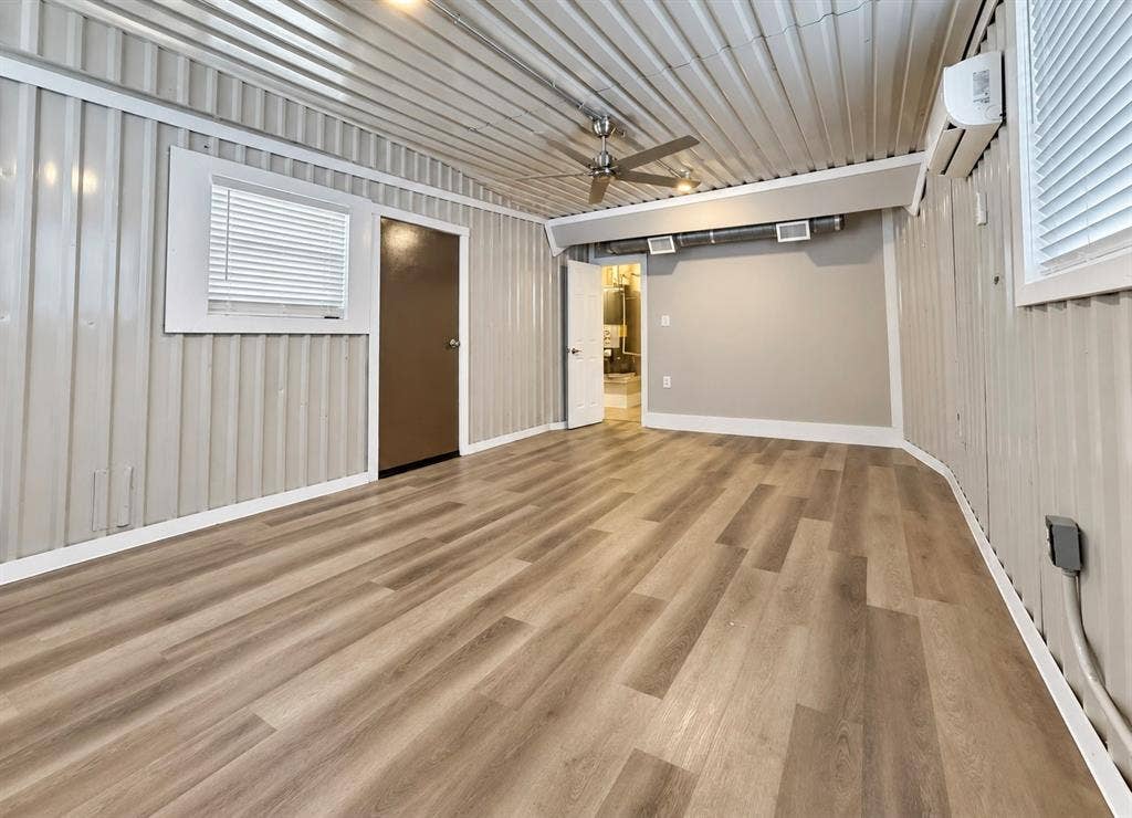 4227 Delano Place, Dallas, TX 75204 Interior space featuring corrugated metal walls and ceiling, wood-finish flooring, a ceiling fan, and a wall-mounted mini-split system