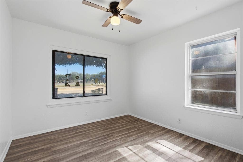 2009 S 1st Street, Garland, TX 75041 Interior space featuring wood-finish flooring, two windows, and a ceiling fan with integrated light fixture