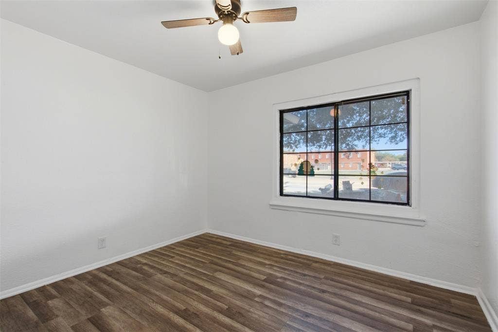 2009 S 1st Street, Garland, TX 75041 Neutral-toned interior featuring wood-finish flooring, a multi-pane grid window with a dark frame, and a ceiling fan with integrated lighting