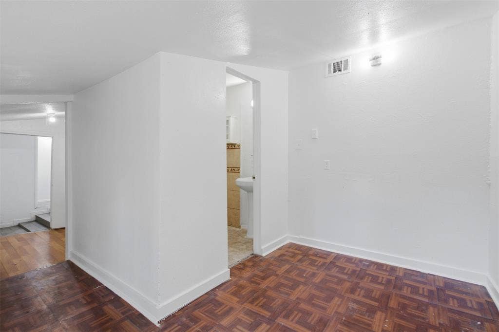 2009 S 1st Street, Garland, TX 75041 Interior space featuring parquet wood-finish flooring, smooth white walls, and a built-in pedestal sink