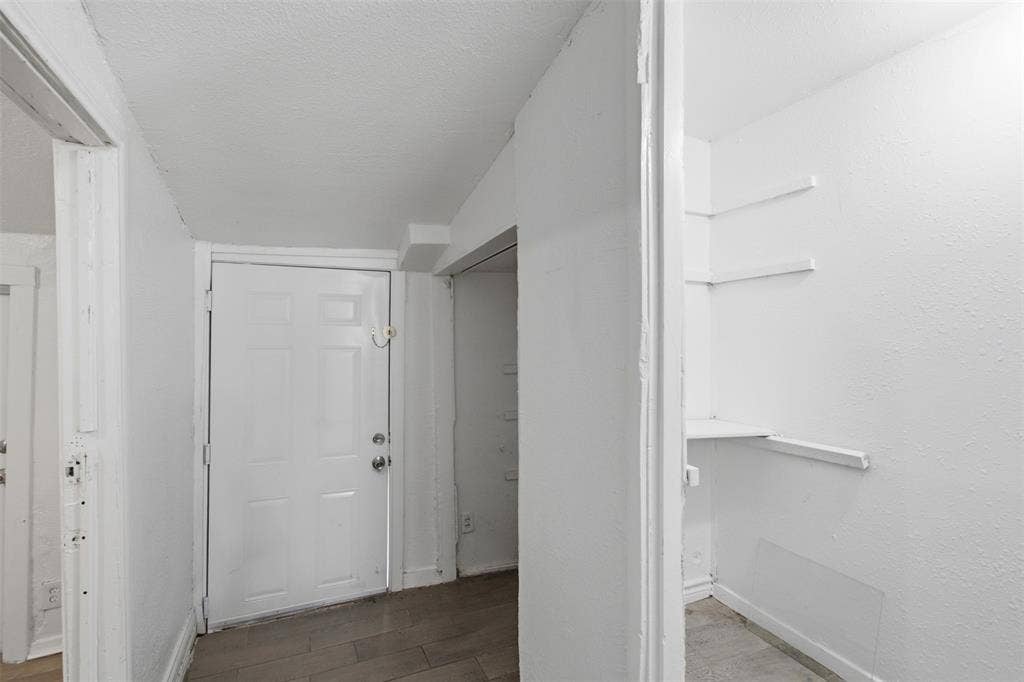 2009 S 1st Street, Garland, TX 75041 Six-panel interior door, wood-finish flooring, and built-in wall shelving