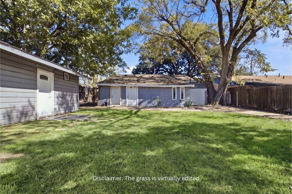 2009 S 1st Street, Garland, TX 75041 Expansive backyard featuring a large grass area, mature trees, wood privacy fencing, and a detached outbuilding with horizontal siding