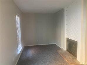 8110 Skillman Street, #1053, Dallas, TX 75231 Unfurnished living room featuring a glass covered fireplace and dark colored carpet