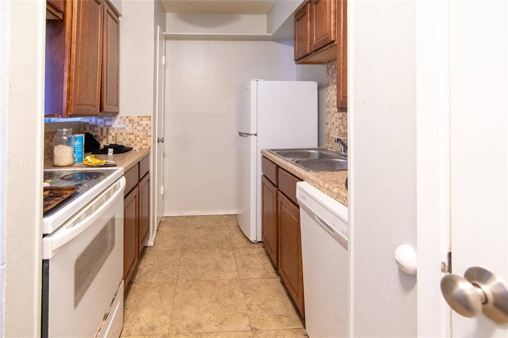 8110 Skillman Street, #1053, Dallas, TX 75231 Kitchen featuring white appliances, tasteful backsplash, brown cabinetry, light countertops, and light tile patterned flooring