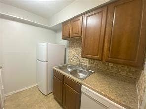 8110 Skillman Street, #1053, Dallas, TX 75231 Kitchen with decorative backsplash, brown cabinetry, light countertops, and white appliances