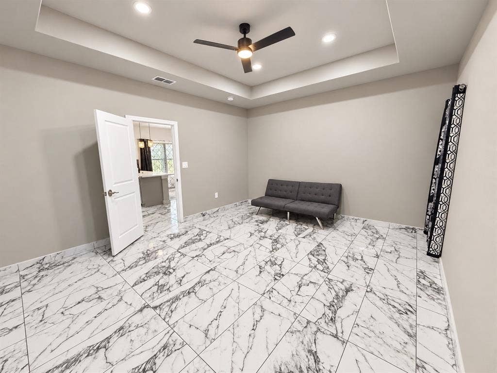 707 N Blanche Street, Terrell, TX 75160 Tray ceiling with integrated recessed lighting, large-format veined tile flooring, and a central matte black ceiling fan