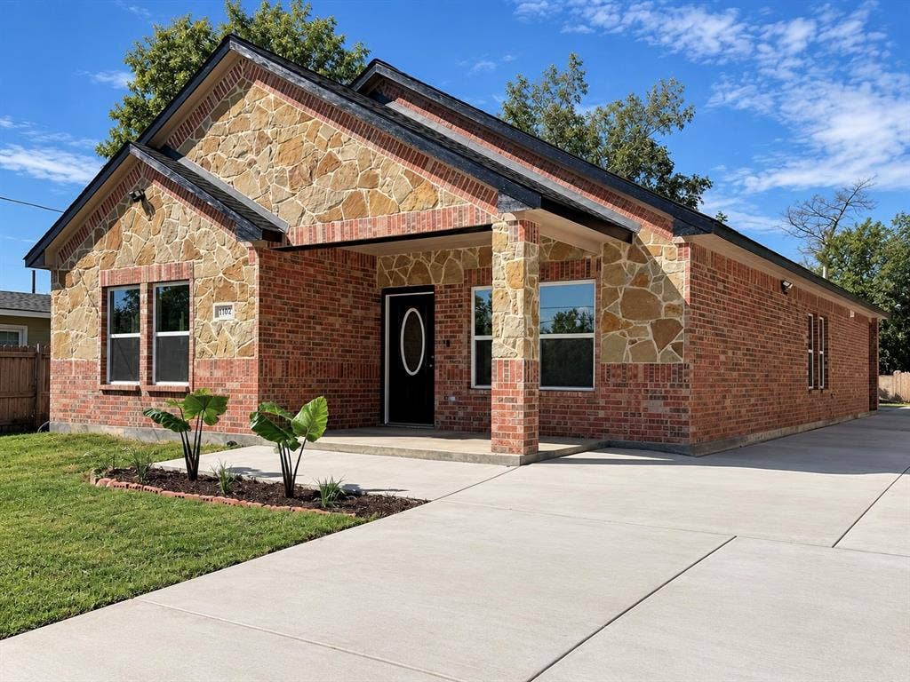 707 N Blanche Street, Terrell, TX 75160 Exterior facade featuring a brick and stone veneer, gable roofline, covered front porch, and concrete driveway