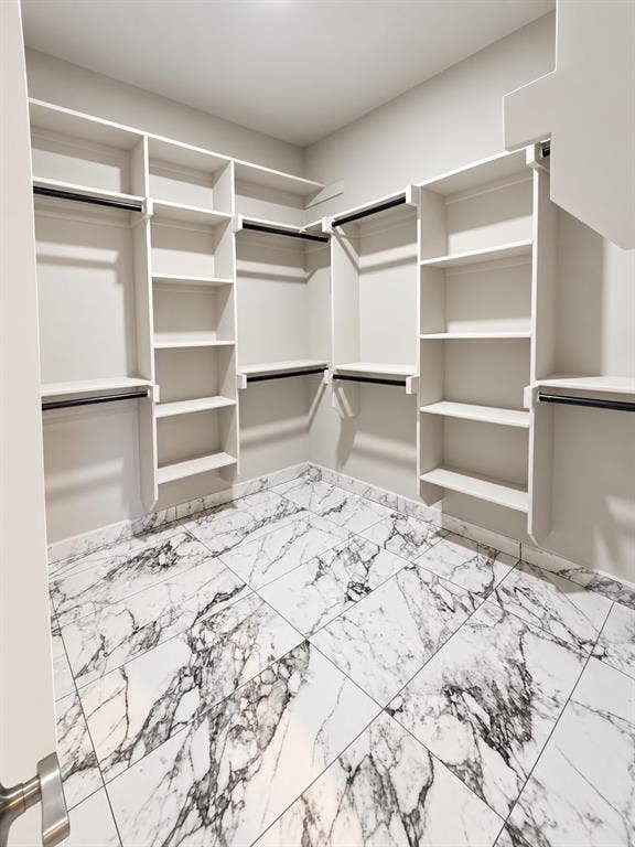 707 N Blanche Street, Terrell, TX 75160 Walk-in closet featuring extensive built-in white shelving, integrated hanging rods, and large-format porcelain tile flooring with a veined pattern