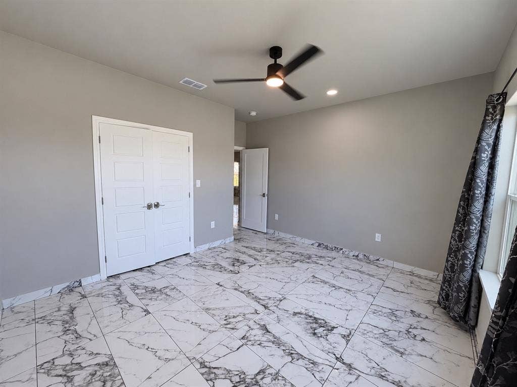 707 N Blanche Street, Terrell, TX 75160 Room featuring large-format tile flooring with a marble-finish pattern, double-door closet, recessed lighting, and a modern matte-finish ceiling fan