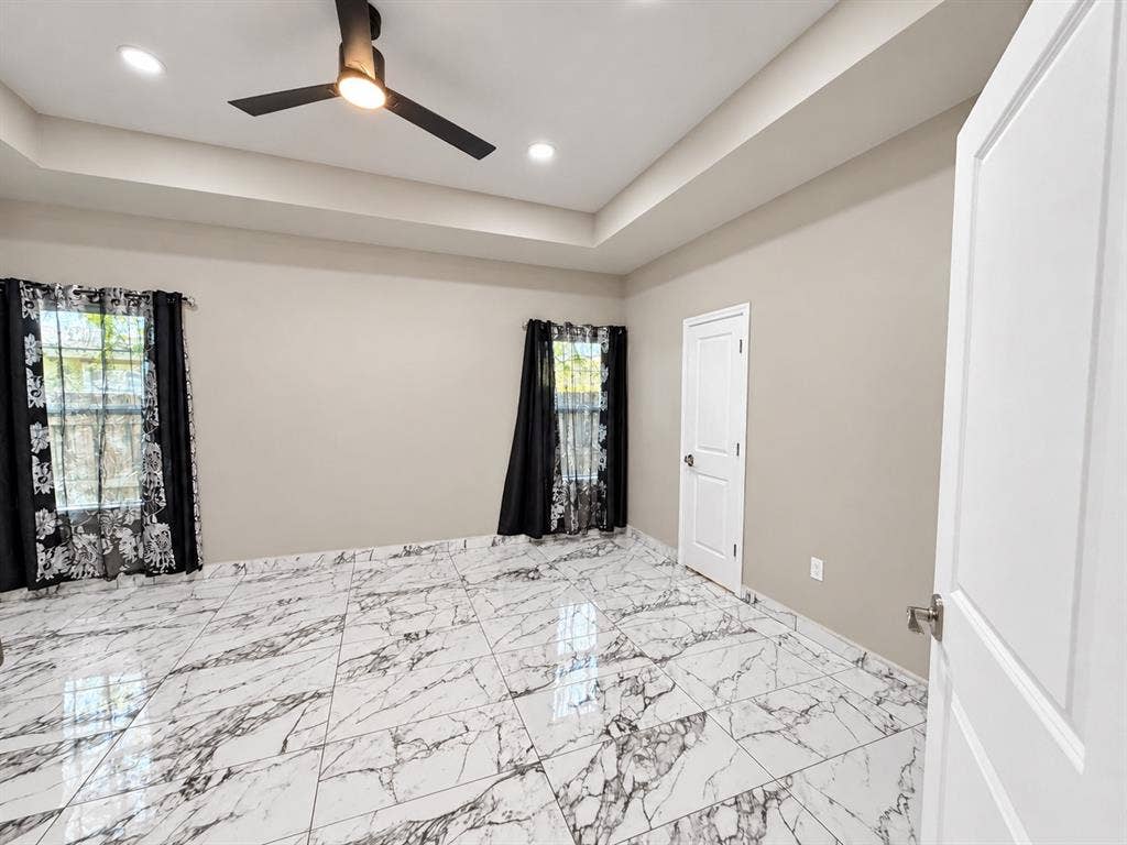 707 N Blanche Street, Terrell, TX 75160 Tray ceiling featuring recessed lighting and a matte black ceiling fan, complemented by large-format high-gloss patterned tile flooring