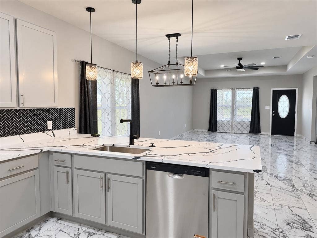 707 N Blanche Street, Terrell, TX 75160 Kitchen featuring light gray shaker-style cabinetry, quartz countertops with prominent veining, a black herringbone tile backsplash, stainless steel dishwasher, and polished stone-finish flooring