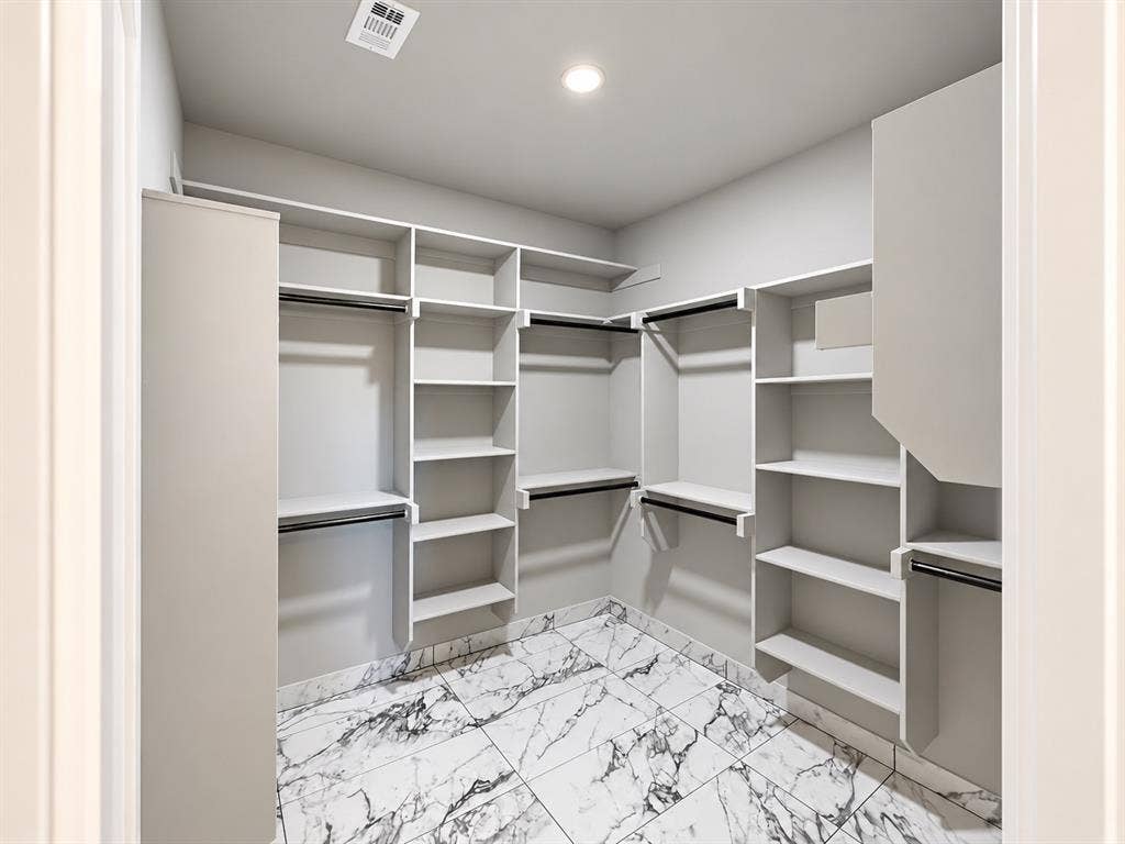 707 N Blanche Street, Terrell, TX 75160 Walk-in closet featuring floor-to-ceiling white built-in shelving, multiple hanging rods, and stone-finish tile flooring