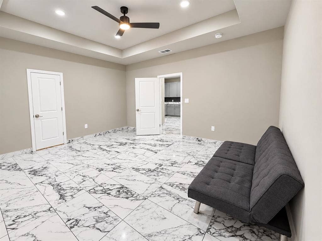707 N Blanche Street, Terrell, TX 75160 Tray ceiling featuring recessed lighting, large-format stone-patterned tile flooring, and a matte black ceiling fan with integrated light
