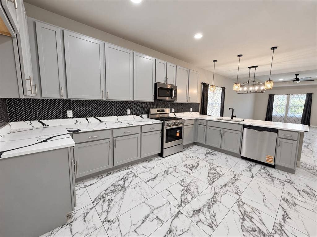 707 N Blanche Street, Terrell, TX 75160 Kitchen featuring light gray shaker cabinetry, quartz countertops with veining, a black herringbone tile backsplash, stainless steel appliances, and large-format patterned tile flooring