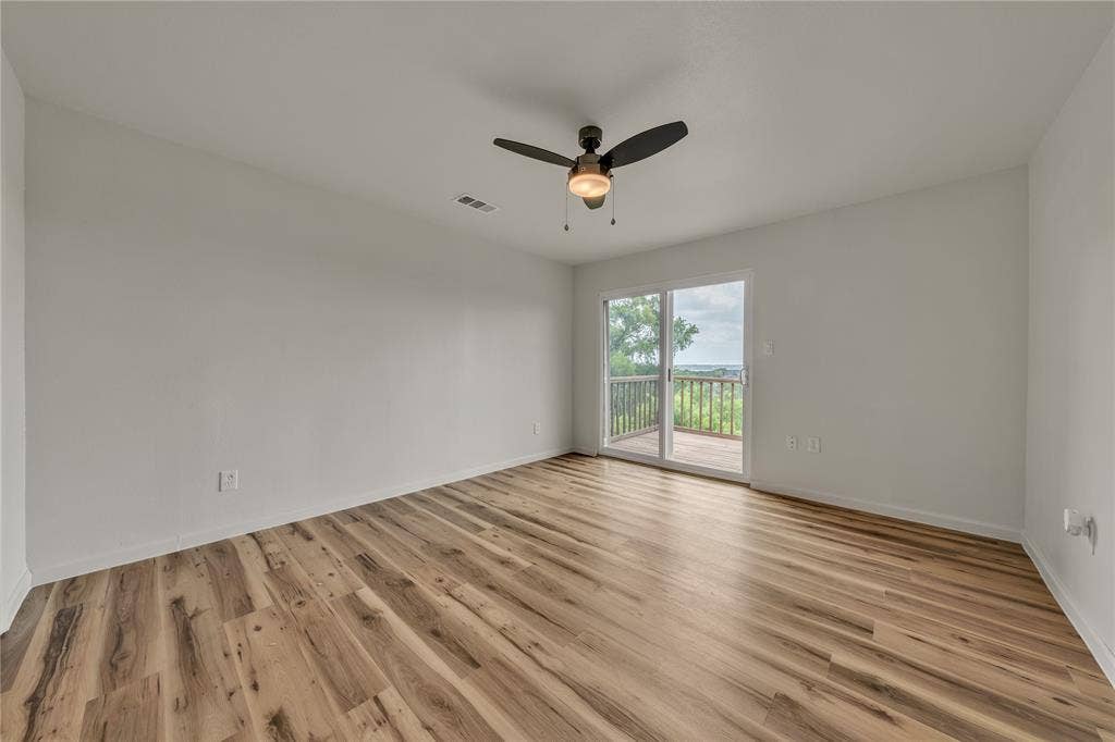 1719 Boot Hill Road, Granbury, TX 76049 Room featuring wood-finish flooring, a ceiling fan with integrated lighting, and a sliding glass door providing external access to a wooden deck