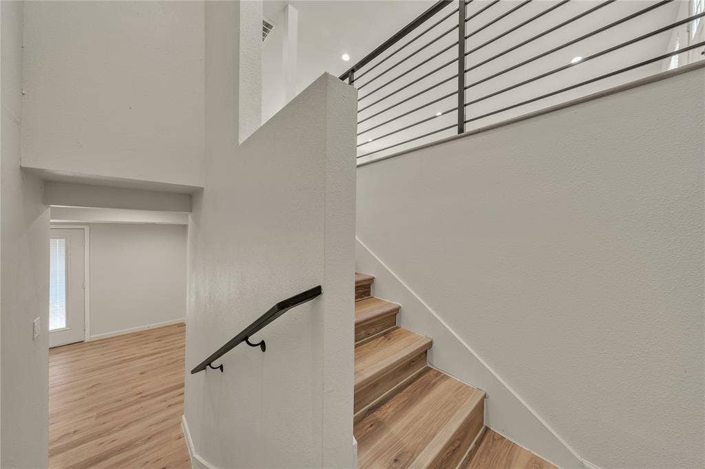 1719 Boot Hill Road, Granbury, TX 76049 Staircase featuring wood-finish treads, a dark metal handrail, and a metal horizontal-bar railing